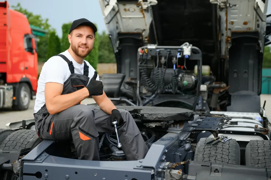 A mechanic finished fixing the truck and giving a thumbs up.