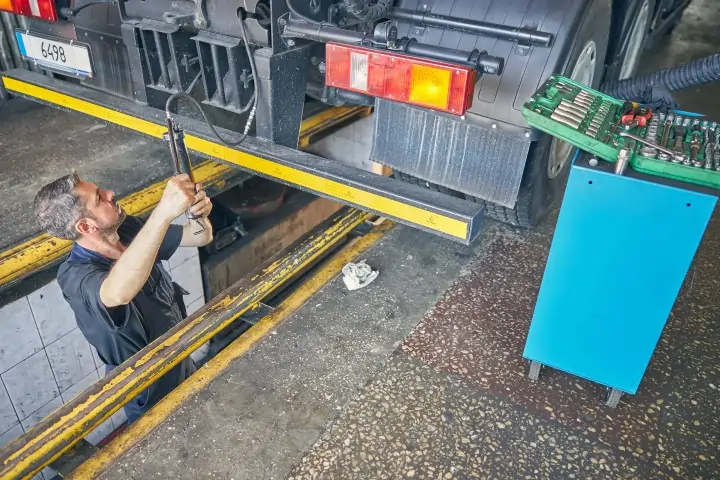 A working mechanic checking the pressure of the wheels of a truck.