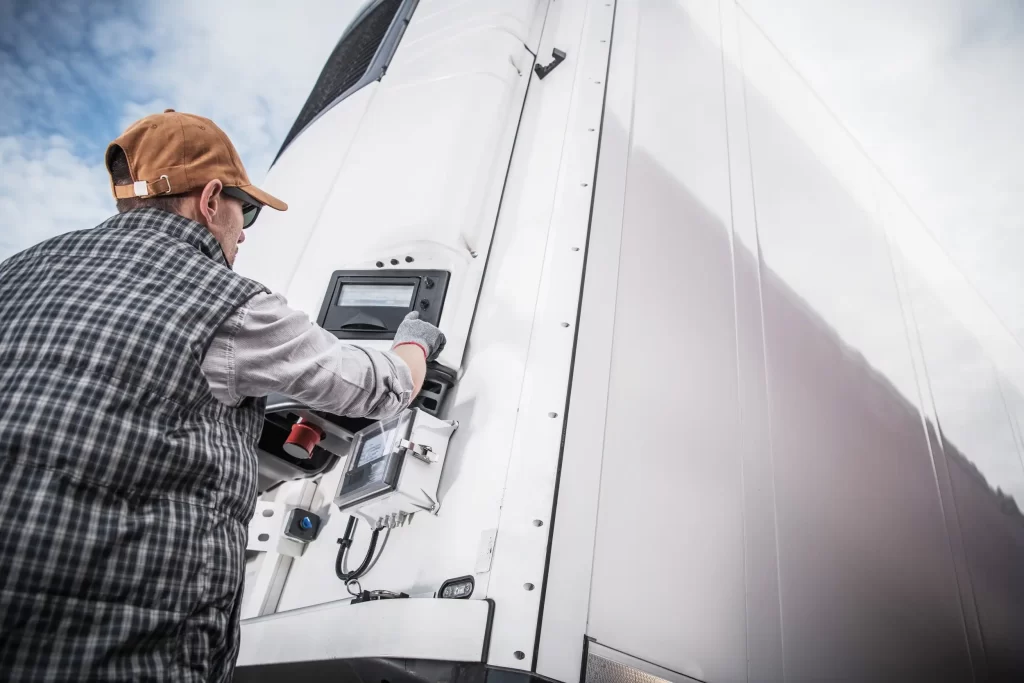 Reefer repair technician checking temperature settings of a malfunctioning refrigeration unit.