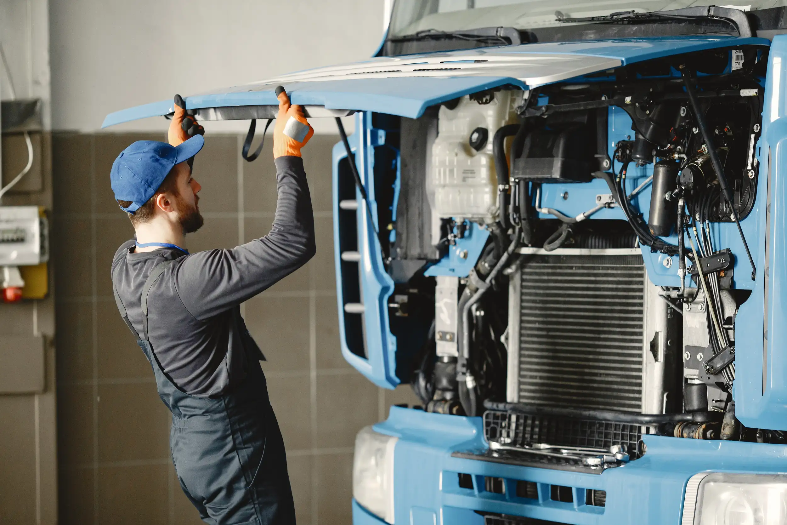 A mechanic opening the hood trunk of a trailer truck.