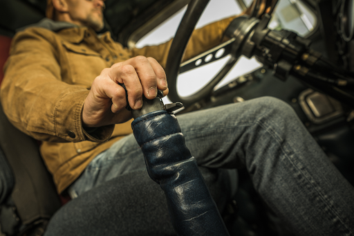 Truck driver operating a manual gear shifter, emphasizing driver interaction with transmissions.