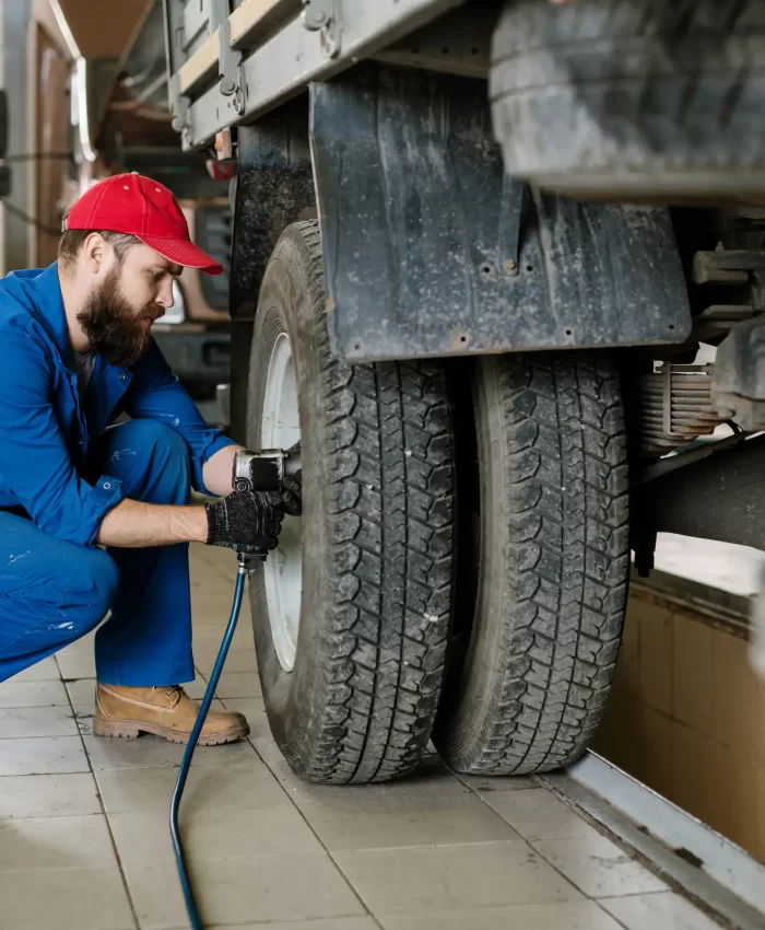 A bearded mechanic checking the tires pressure of a truck.