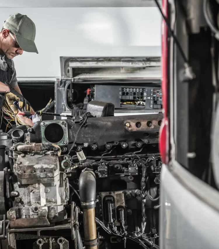 An image of a uniformed mechanic fixing the wirings and checking the parts from a trailer truck.