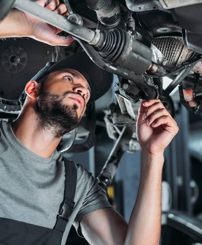 A mechanic repairing under a trailer truck.