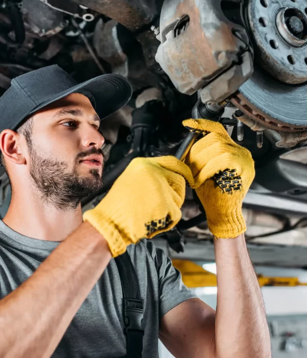 A professional mechanic in uniform adjusting the brake pad of a truck