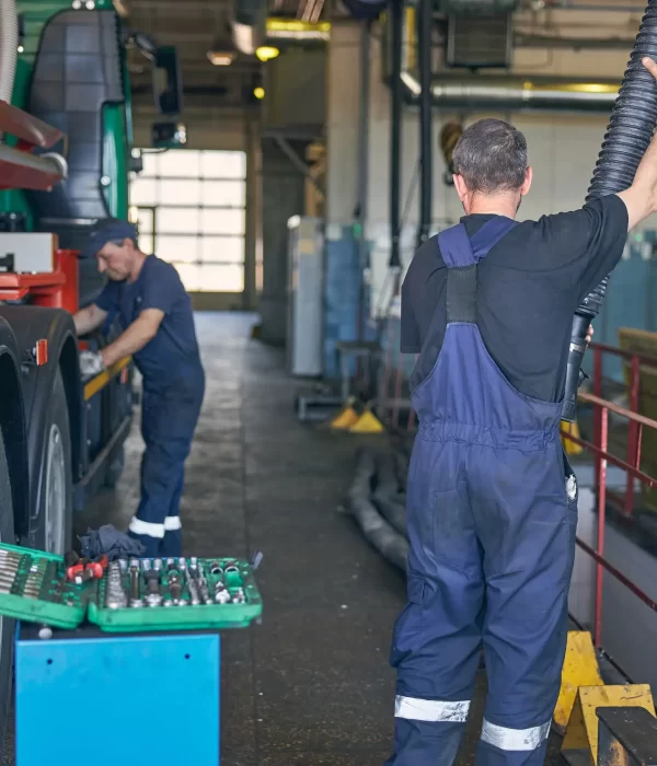 Two male mechanic ensuring the safety and condition of a trailer truck.