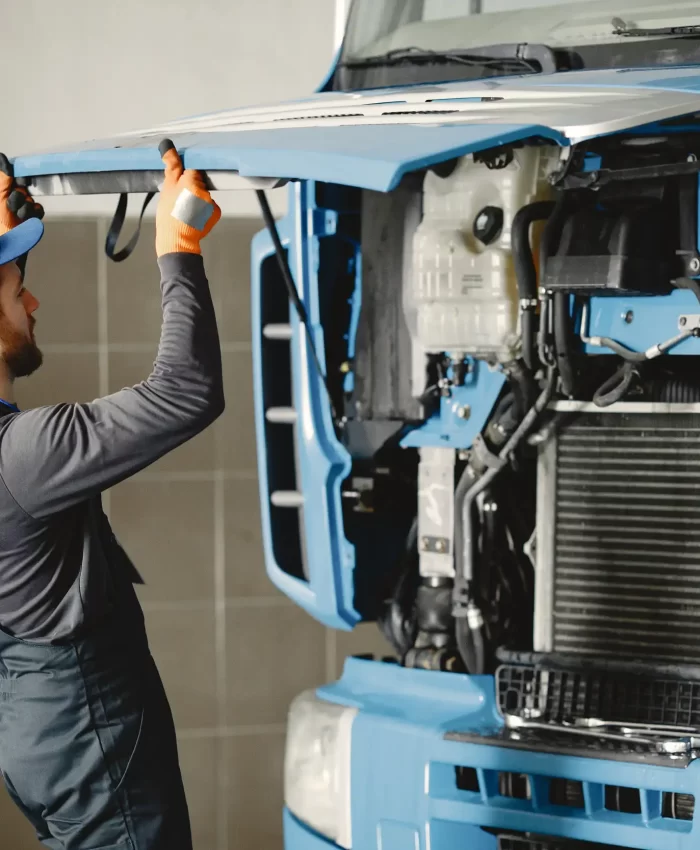 A mechanic opening the hood trunk of a trailer truck.